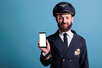Smiling airplane captain showing modern phone with blank white screen, smartphone advertising...