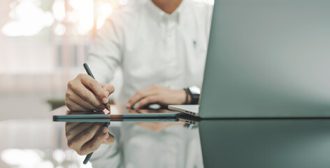 young man writing business plan on digital tablet at desk in modern coworking office. copy space