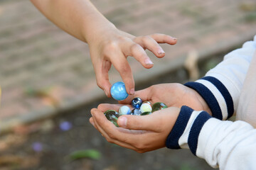 Children playing with marbles in the school yard at break time.Traditional game, shared section of...