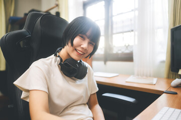 Young adult asian woman stay at home  wear headphone listening music online