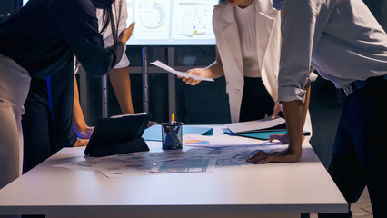 A group of businesspeople share their ideas to expedite the completion of the project until late at...