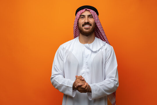 Portrait of young smiling Arab man on orange background