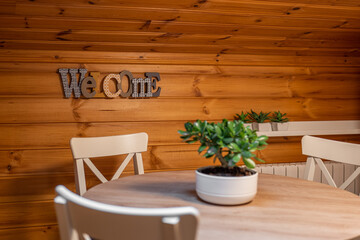Dining room with table, chairs and word welcome on wooden wall in rural house. Selective focus.