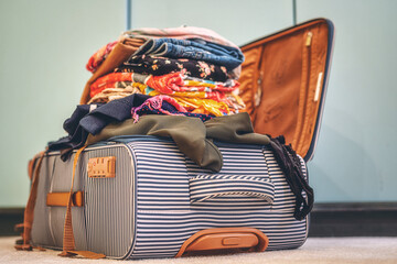 Open suitcase full of clothes in room.