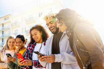 Happy Multiracial Group look at the phone smiling - multi ethinic group of young people laugh.   Student friends of various races laughing online social . Friends Concpet 