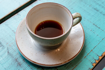 Taza pequeña de café sobre una mesa azul. 