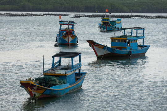 Brightly colored Vietnamese fishing boats at Can Gio in afternoon light.