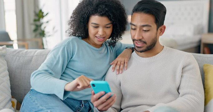 Happy multiracial couple on couch with phone in living room chatting, scrolling social media and streaming movie. Black woman and asian man on sofa online using smartphone for internet and plan date.