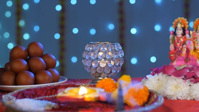 A Puja Thali with a Diya - Lord Ganesha and Lakshmi Ji Idol  Diwali. Idols of Lord Ganesha and Lakshmi Devi with a plate of sweets - a colored background  Diwali Puja  Indian festival