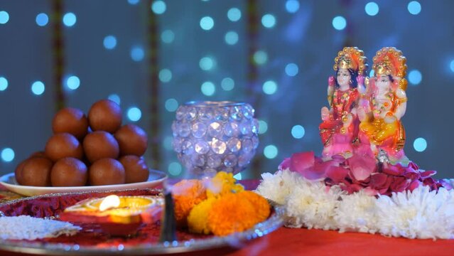 Female keeping a Puja Thali near Lord Ganesha and Goddess Lakshmi - Diwali Puja. Idols of Ganesh Ji and Lakshmi Devi decorated with flower petals and a plate of sweets - a Hindu festival  colorful ...