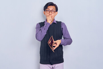 Portrait of shocked young Asian man wearing shirt and vest showing empty brown wallet isolated on white background - obrazy, fototapety, plakaty