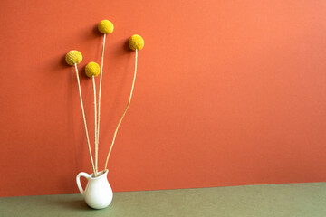 Vase of yellow dry flowers on khaki table. red wall background. home interior decoration