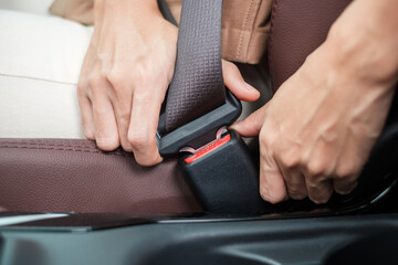 woman driver hand fastening seat belt during sitting inside a car and driving in the road. safety,...