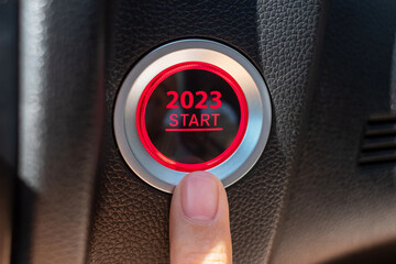 Finger press a car ignition button with 2023 START text inside  automobile. New Year New You,...