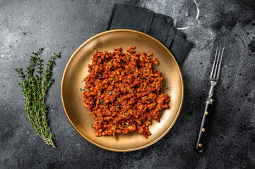 Bolognese sauce with ground beef, stewed with tomato sauce and spices. Black background. Top view
