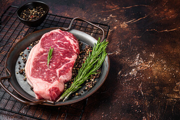 Raw New York or striploin beef meat steak with rosemary and pepper. Dark background. Top view. Copy space