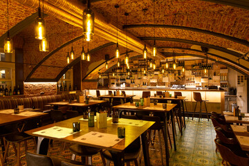 Interior of cozy modern restaurant with a bar counter and lamp lighting