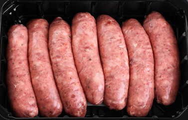 Raw German, Munich, Bavarian, sausages in a black plastic container.