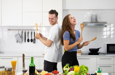 Funny couple man and woman dancing in kitchen during cooking at home together. - 533297872