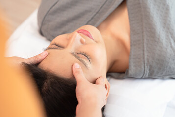 Young woman enjoying face massage in spa salon