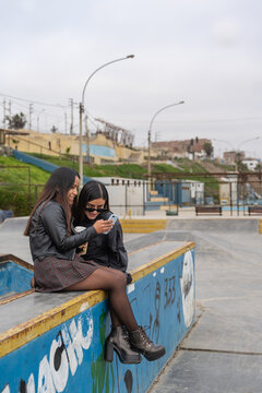 Two young women using a mobile in an urban park