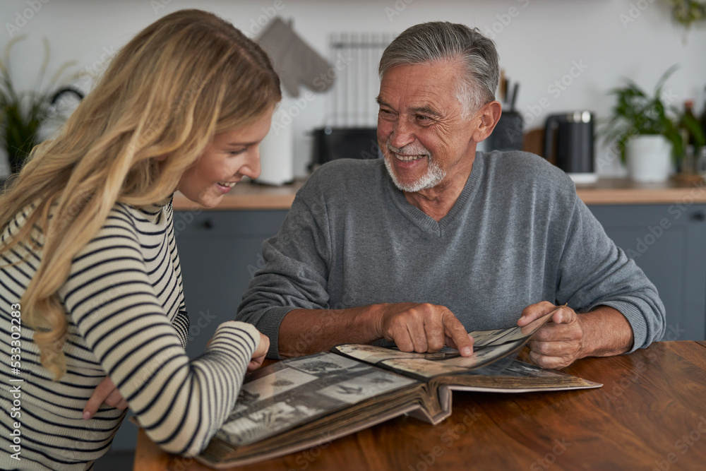 Wall mural Senior man meeting with adult daughter and looking at old pictures in album