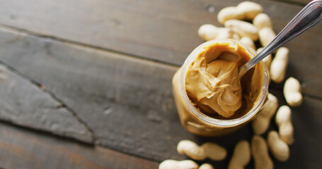 Image of close up of peanut butter and peanuts on wooden background