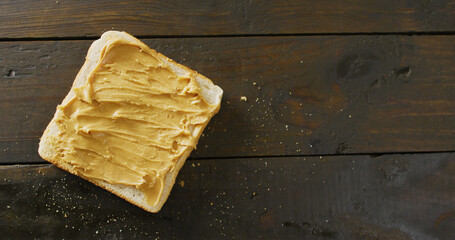 Image of close up of toast with peanut butter on wooden background