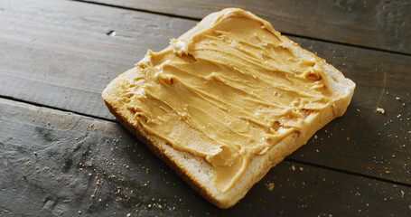 Image of close up of toast with peanut butter on wooden background