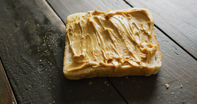 Image of close up of toast with peanut butter on wooden background