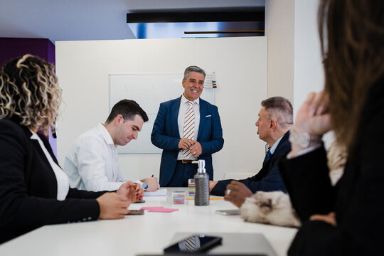 Smiling mature businessman discussing with colleagues in meeting at office