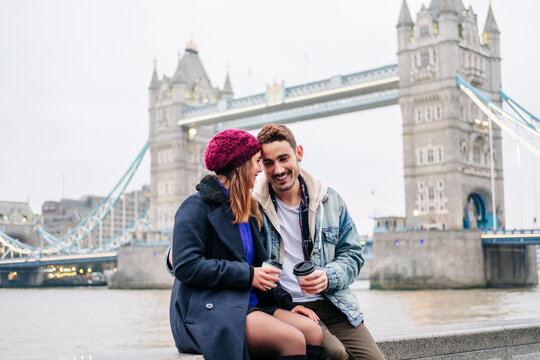 London, United Kingdom. A couple of boy and girl sitting next to Tower Bridge