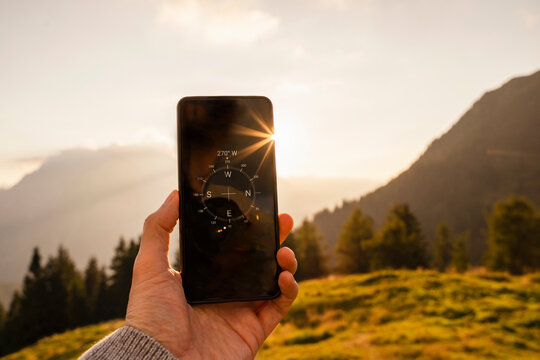 Hand of man showing compass on mobile phone