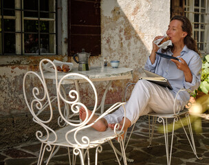 Mature woman enjoying croissant for breakfast on rooftop