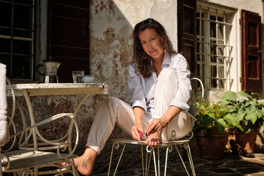 Smiling woman applying nail polish on toenails at rooftop