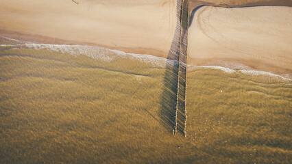 Drone view of wooden posts over sea at beach