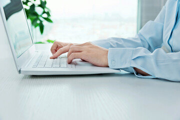 Close-up of businesswoman hand using a laptop on desk