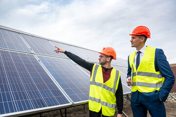 the director of company inspects the work of an employee in  clothing installed solar panels.