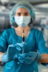 doctor  wearing blue uniform with glove full virus protection holding syringe with medicine