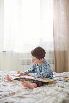 Boy reading book on bed