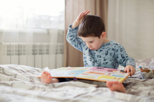 Boy reading book on bed at home