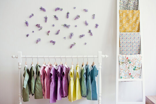 Colorful dresses hanging on rack in front of wall with flowers