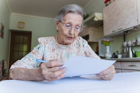 Senior woman reading contract at table in home