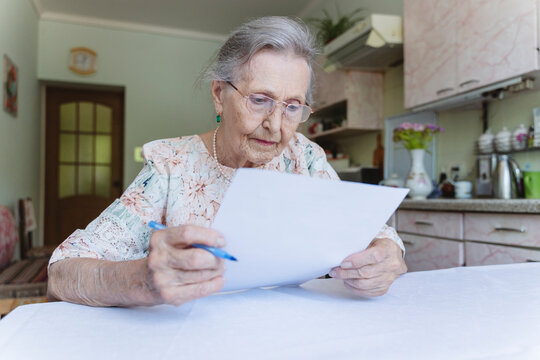 Senior woman reading contract papers at home
