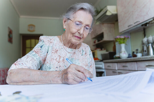 Senior woman signing investment documents on table