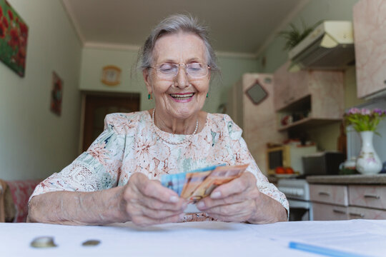 Happy senior woman counting paper currency at home