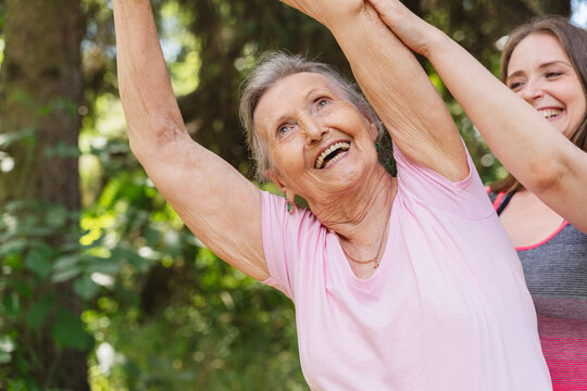 Happy fitness instructor guiding senior woman exercising at park