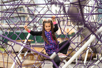 Cute teenage girl in the rope labyrinth kid park attraction