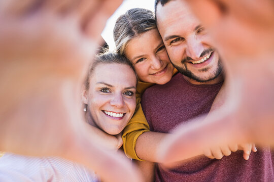 Laughing family embracing and looking through hands at camera
