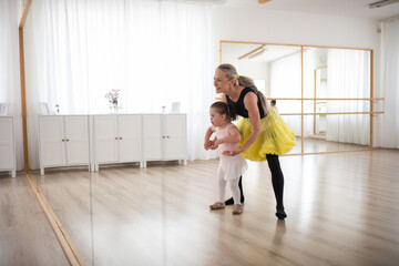 Little girl with down syndrome learning ballet with dance lecteur in ballet studio.